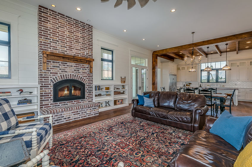 a room with a fireplace, chairs and a couch. on the floor is an ornate area rug