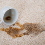 A cup of coffee spilled on a beige carpet