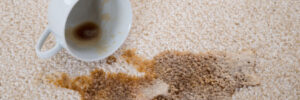A cup of coffee spilled on a beige carpet