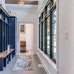 An image of an entryway with a blue painted bench and cabinets, and a runner rug.
