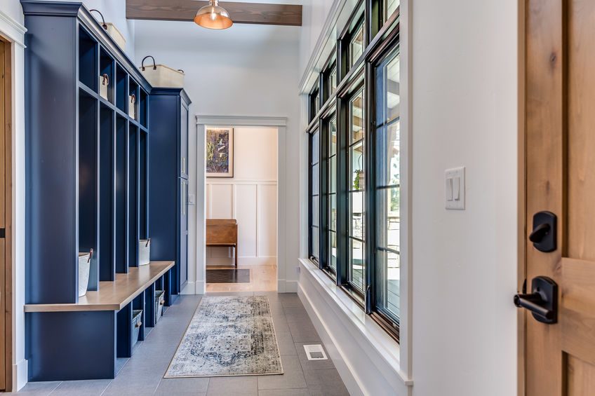 An image of an entryway with a blue painted bench and cabinets, and a runner rug.
