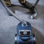 Man with vacuum cleaner cleaning carpeting